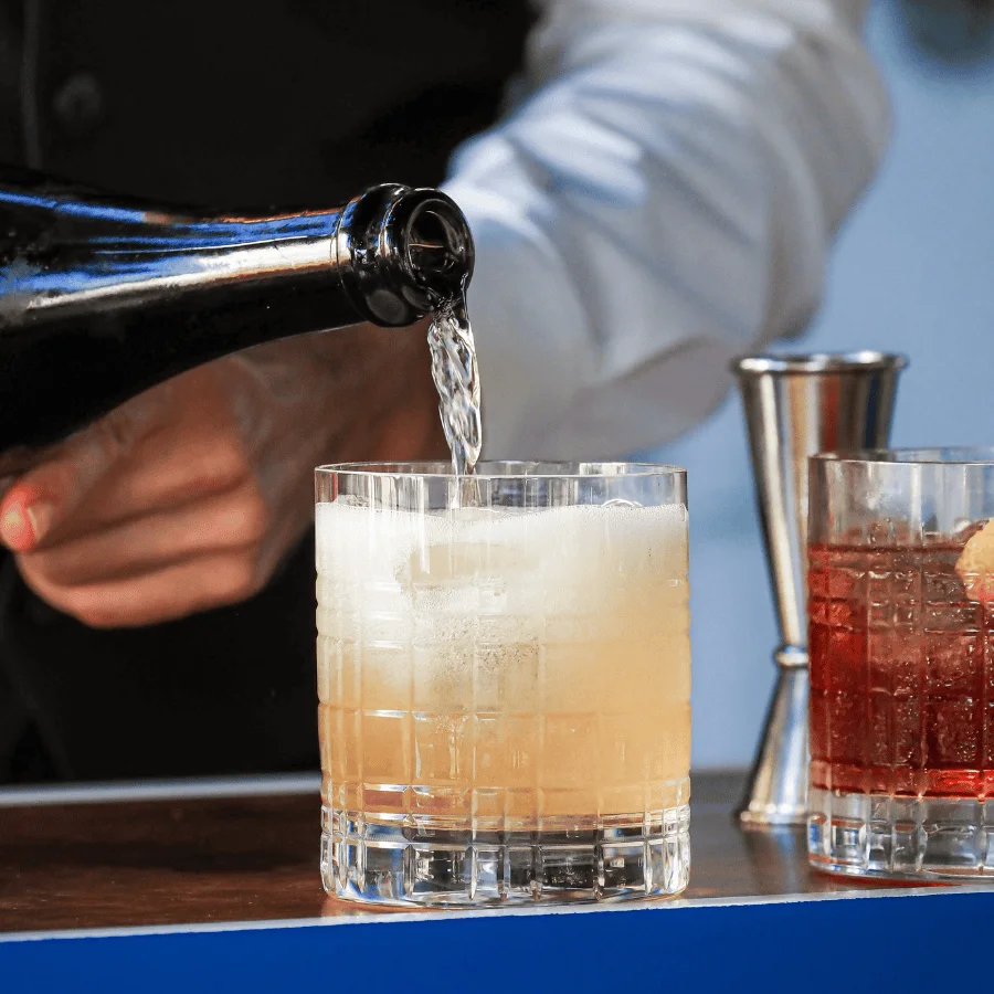 Un camarero sirve un vermú en un vaso con hielo